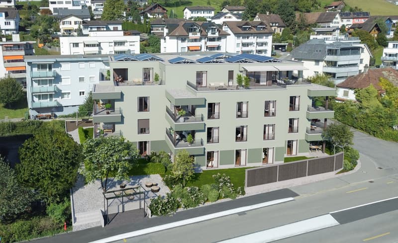 A modern apartment building with multiple floors, solar panels on the roof, balconies, and a garden area.