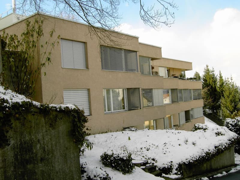 multi-story building, beige facade, white shutters, several balconies, snowy surroundings