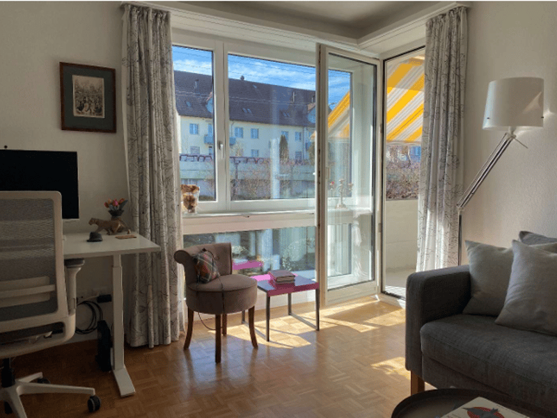 Living room with desk, chair, couch, lamp, picture frame, and balcony with view