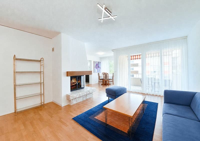 Wohnzimmer mit Cheminée mit Einsicht in den Essbereich/Küche und Zugang in den Balkon