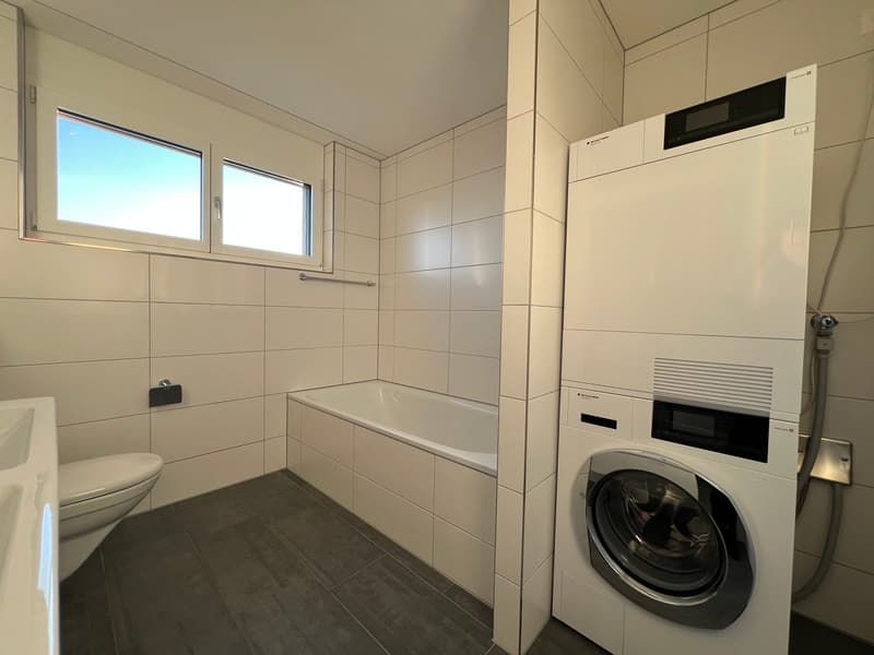 tiled walls, bathtub, white sink, white toilet, washing machine