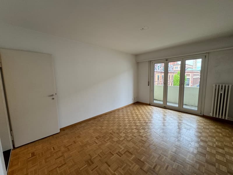 empty room, wooden parquet floor, white walls, sliding glass doors to balcony, white radiator