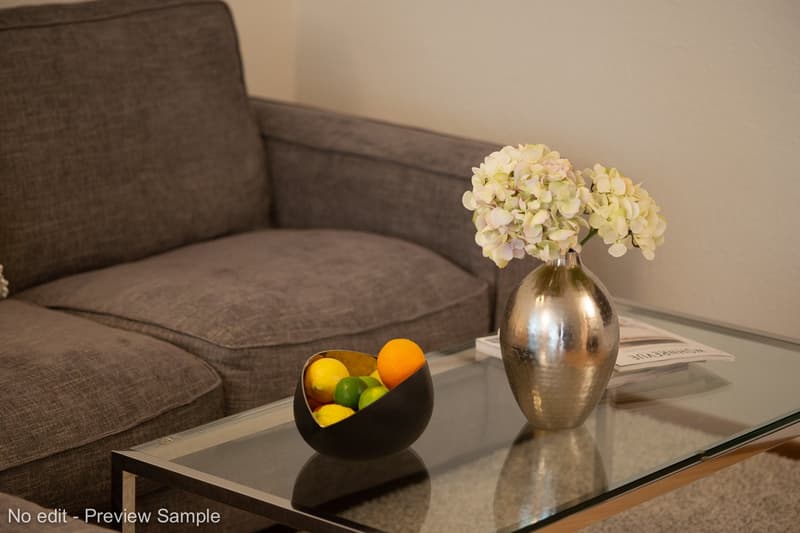 Sofa, glass table with fruits and flowers in vases, magazines