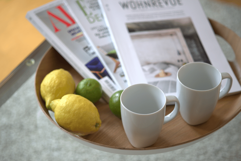 a bowl of fruits with a magazine and two white cups