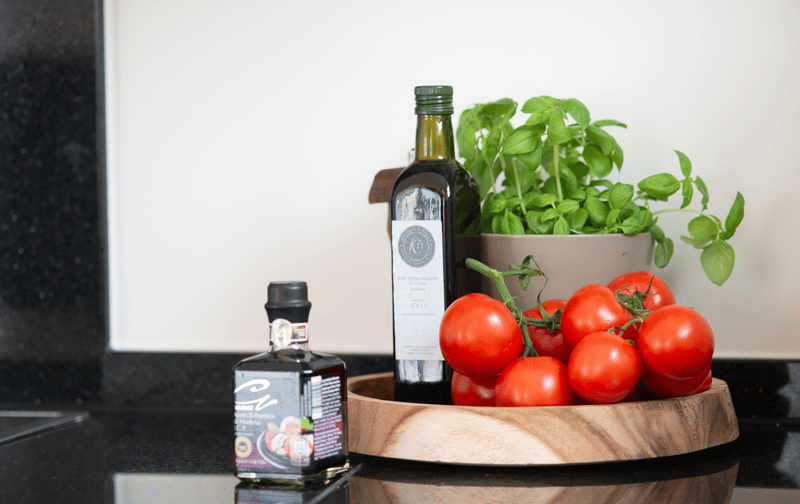 kitchen counter with oil bottles, plant and tomatoes