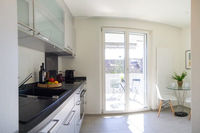 kitchen, black countertop, modern white cabinets, double sink, balcony, round table, chairs