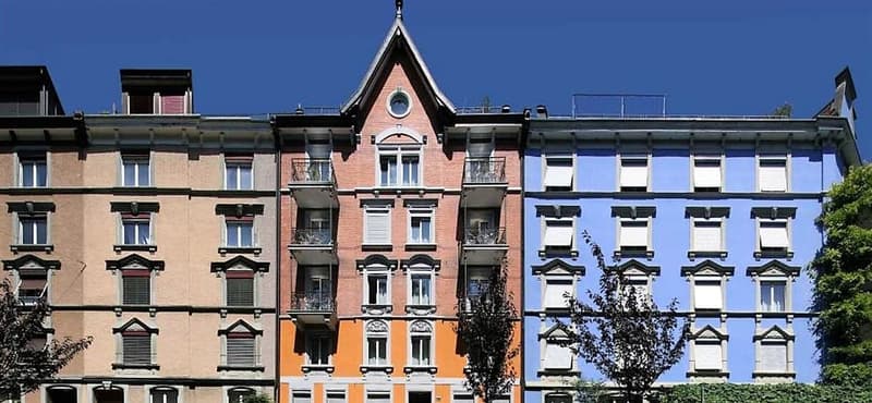 Large 4 story building with many windows, balconies, and ornate decorations.
