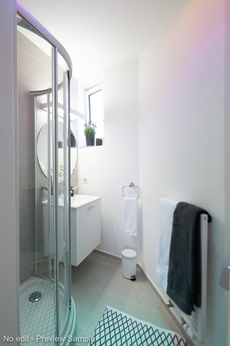 Bathroom with glass shower enclosure, white vanity, and towel rack