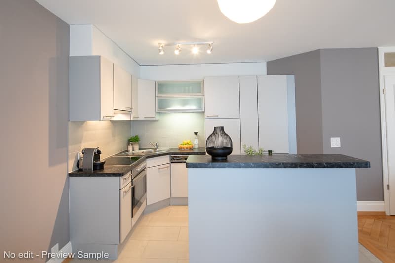 Modern kitchen with white cabinets, black granite countertops, stainless steel appliances including a dishwasher, and track lighting overhead