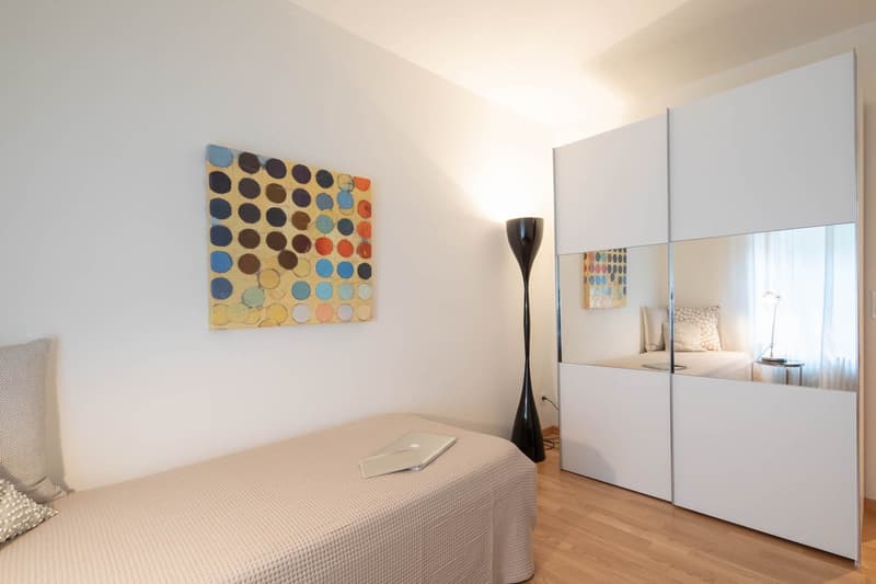 single bed, floor lamp, white wardrobe, painting, wooden floor