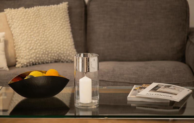 grey couch, grey sofa, glass table, bowl with fruit, candle