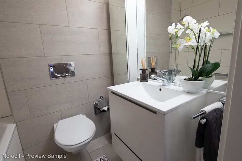modern bathroom with white sink, toilet, large mirror, faucet, towel rack, small flower vase, tiled floor
