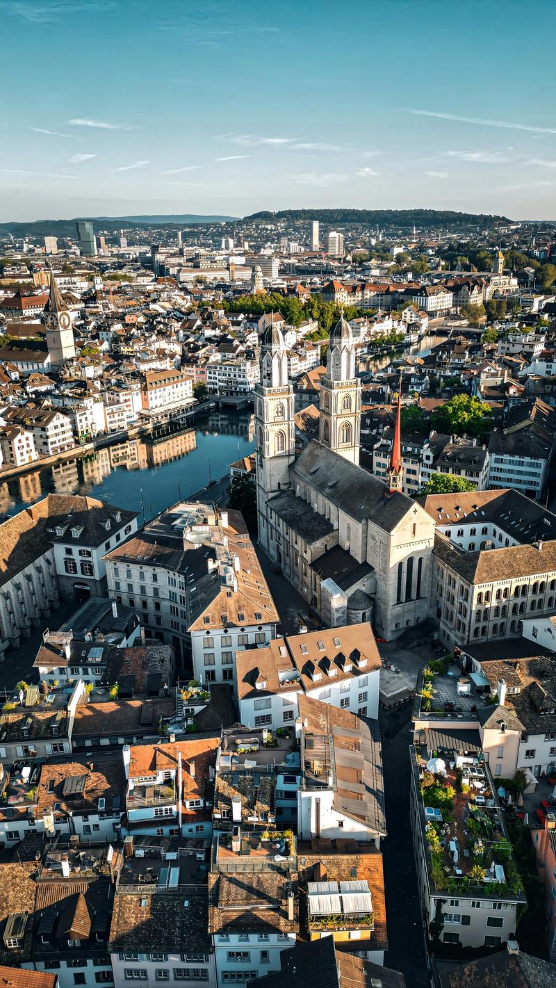Aerial view of a city with many buildings, a river, and a church with two towers.