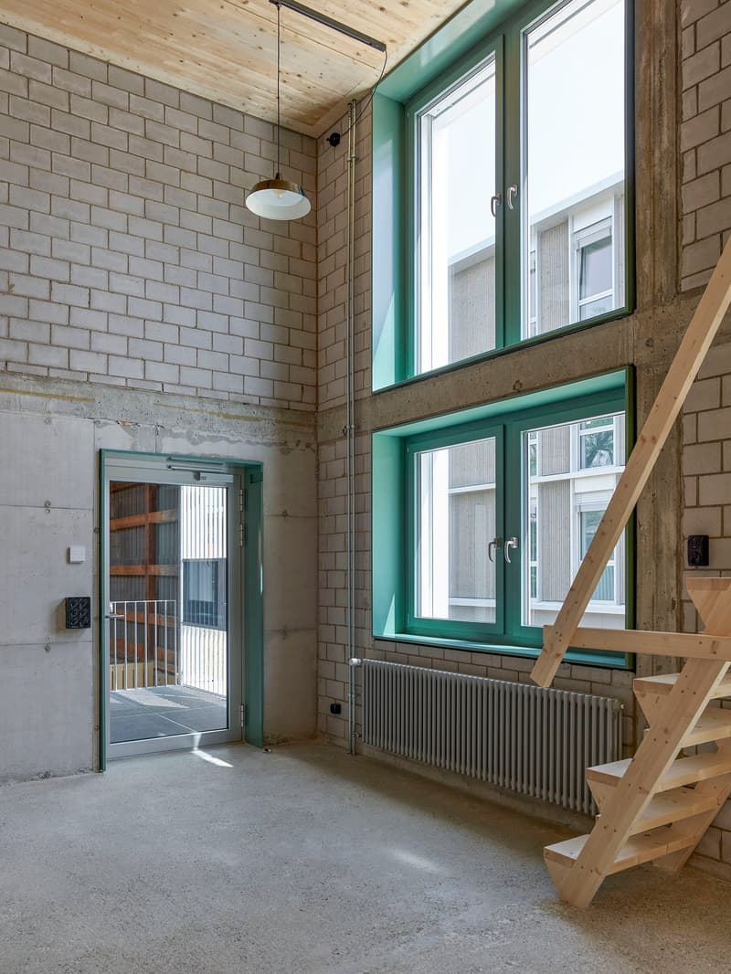 White brick walls, radiators, wooden floor, two doors, windows, wooden stairs