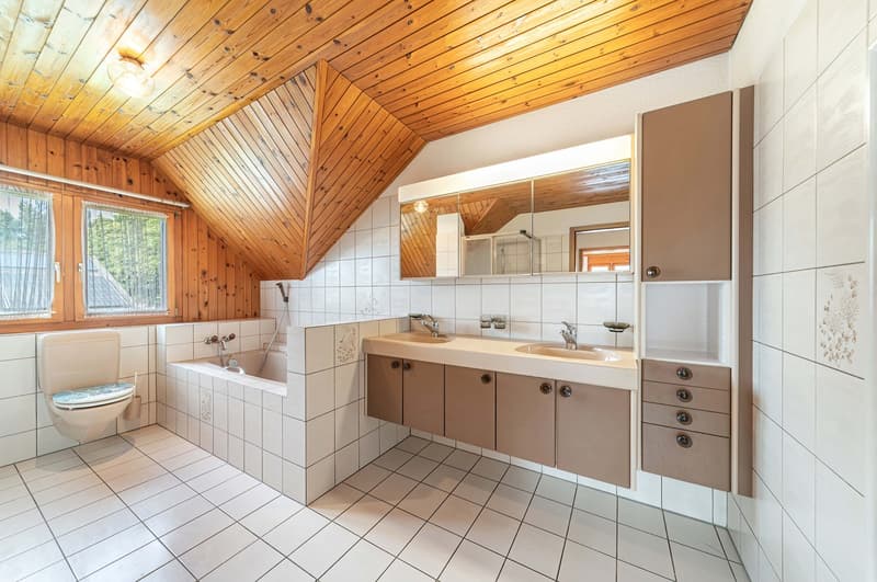 Bathroom with bathtub, sink, mirrors, toilet, tiled floors, wooden ceiling.
