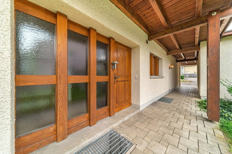 Entrance to a building with wooden framed doors and windows, brick floor and wooden ceiling