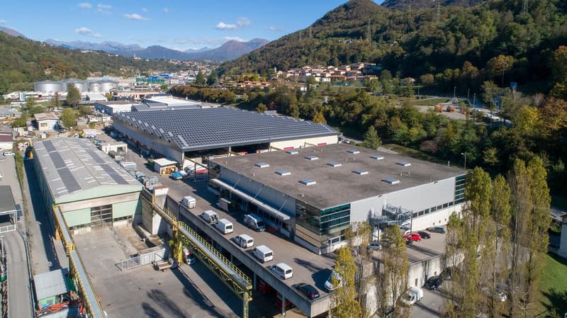 large industrial complex with solar panels, multiple structures, numerous vehicles parked