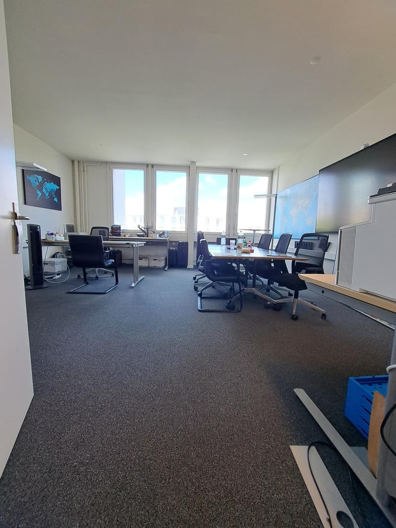 empty office room with tables, chairs, windows, and a map on the wall