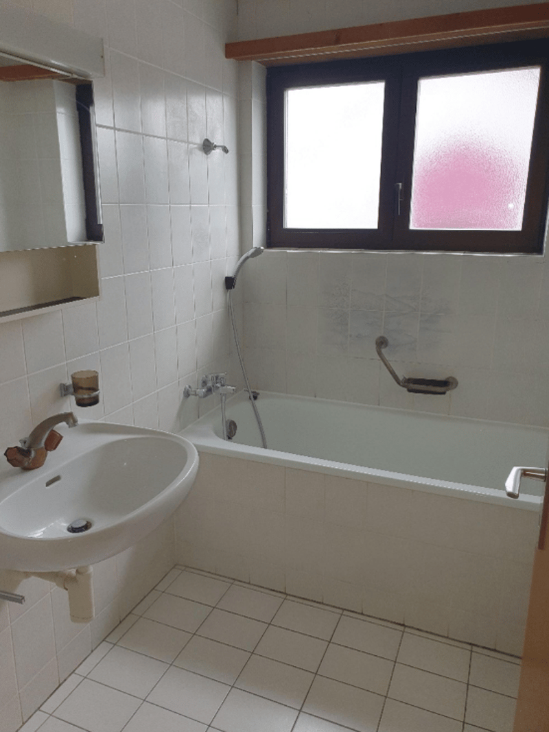 Bathroom with white tiles, bathtub, sink, and window