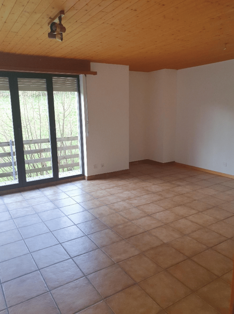 Large open room with tile flooring, white walls, and a sliding glass door leading to an outdoor area.