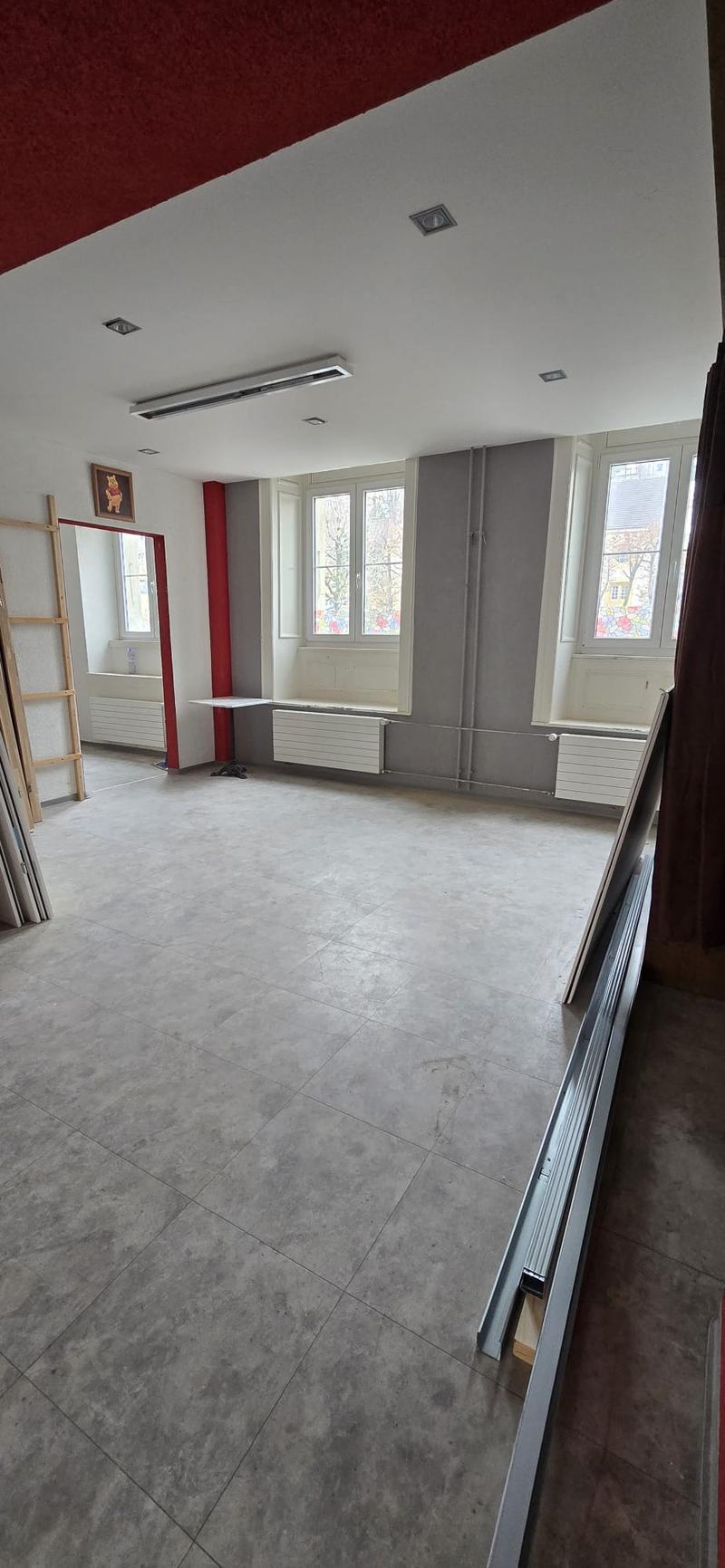 empty room, gray tile floor, white ceiling, white walls, three windows, radiators, wooden ladder