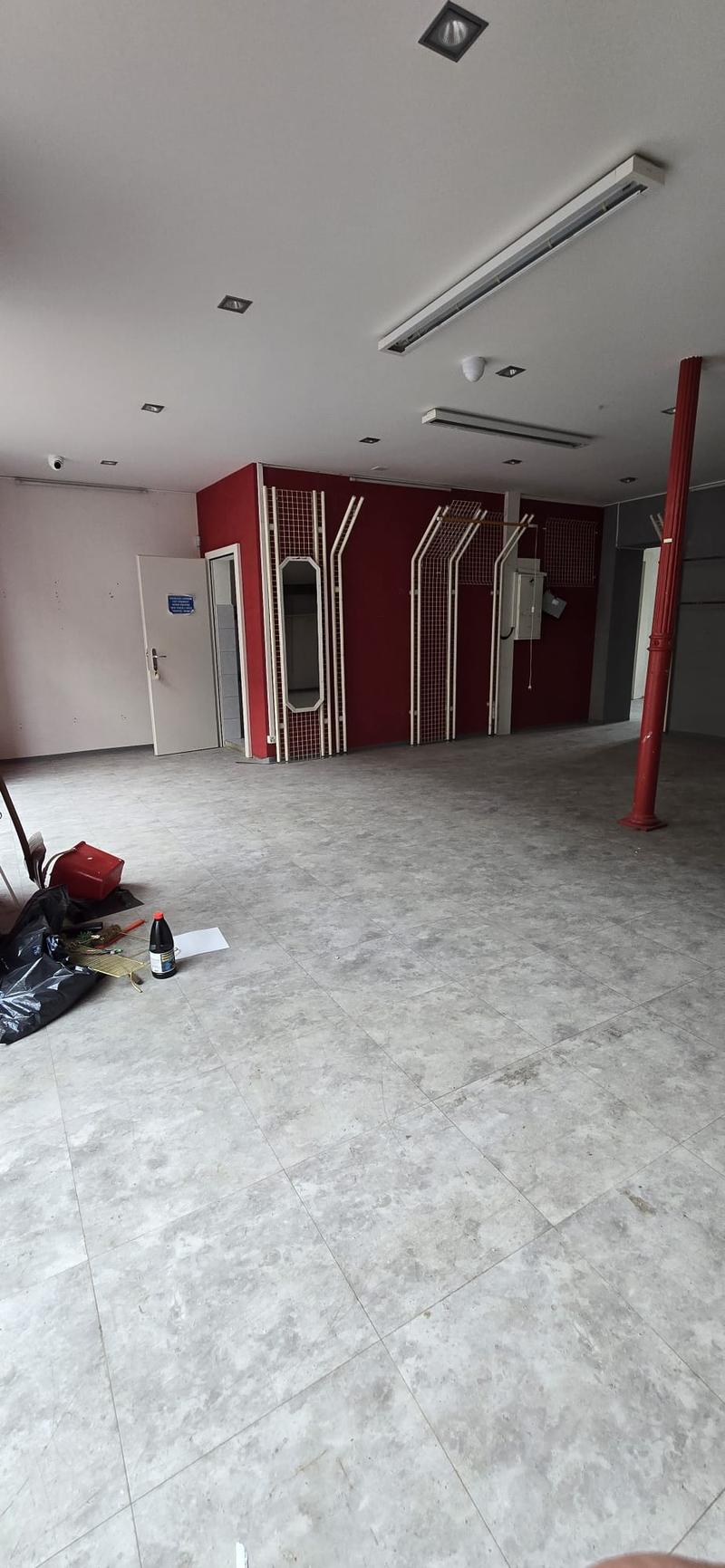 empty room, white tiled floor, red pillar, white door, mirrors, red wall, surveillance camera, lights on the ceiling