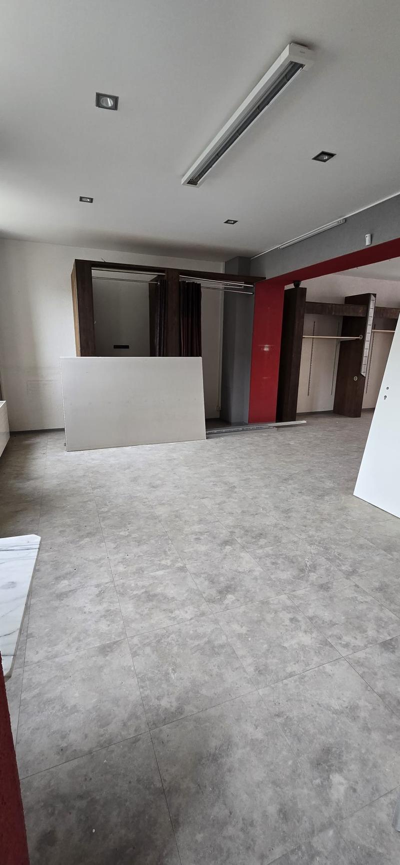 Empty room, grey tiled floor, white and red walls, ceiling lights, large white object, wardrobes