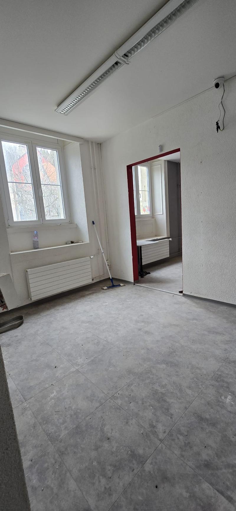 Empty room, tiled floor, radiators, windows, open door