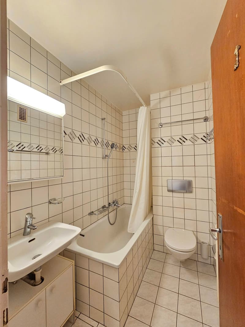 Tiled walls, bathtub, toilet, sink, mirror, shower curtain, lighting, paper roll holder, towel bar, soap dish