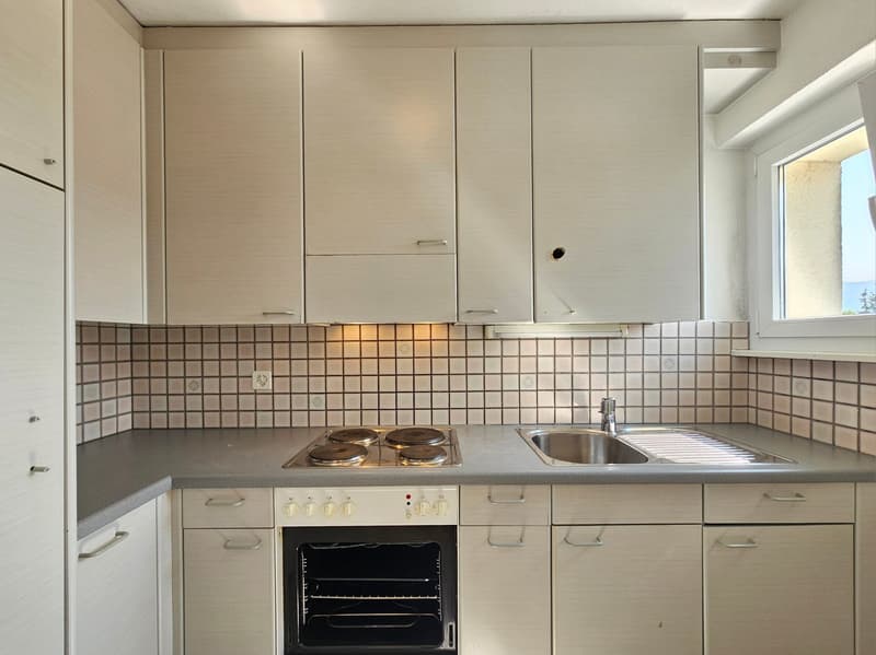 white cupboards, gray countertop, electric stove, oven, stainless steel sink, power outlets, tiled wall