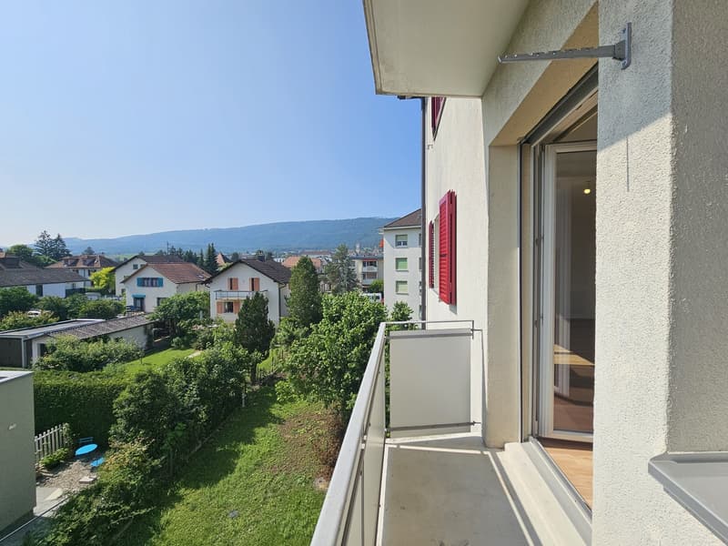 Balcony with a view of the surrounding neighborhood, including houses, trees, and mountains in the distance.