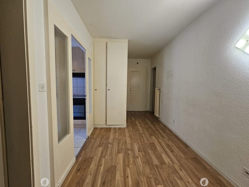 The image shows a room with white walls, a hardwood floor, and a closet along one wall. There is a window and a door visible in the room.
