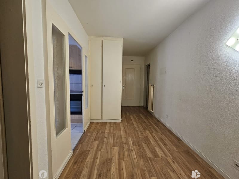 The image shows a room with white walls, a hardwood floor, and a closet along one wall. There is a window and a door visible in the room.