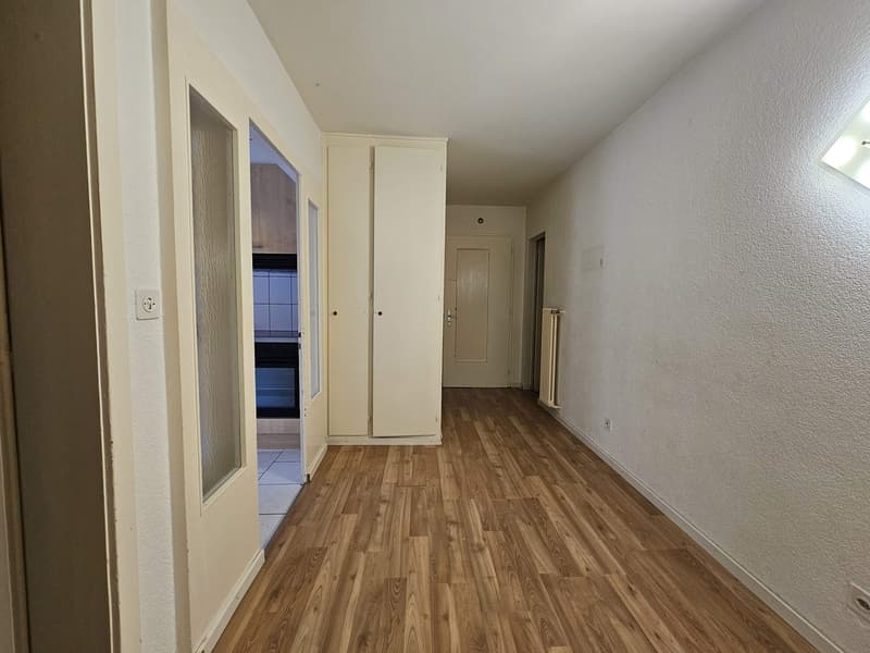 The image shows a room with white walls, a hardwood floor, and a closet along one wall. There is a window and a door visible in the room.
