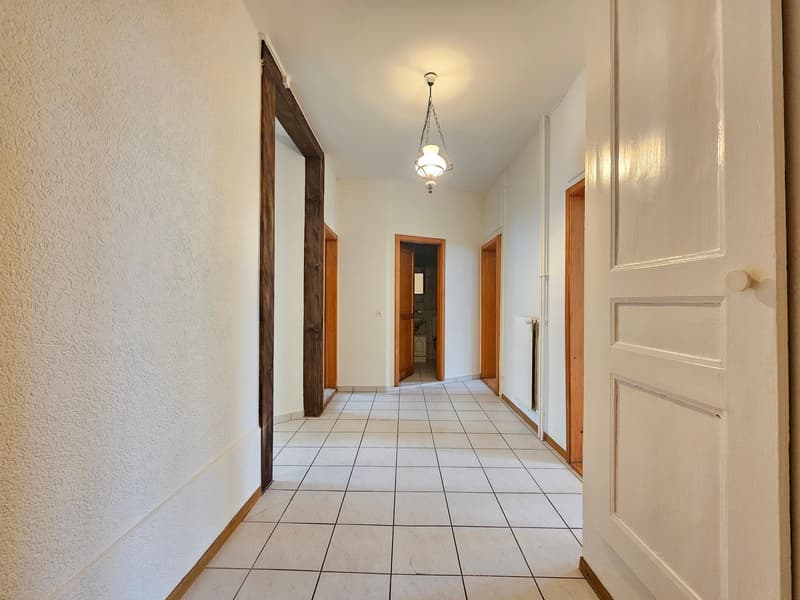 White tile floor, wooden beams, open doors to different rooms, radiator