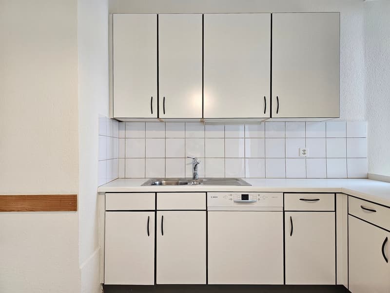 Modern, sleek kitchen with white cabinetry, stainless steel appliances, and tiled backsplash.