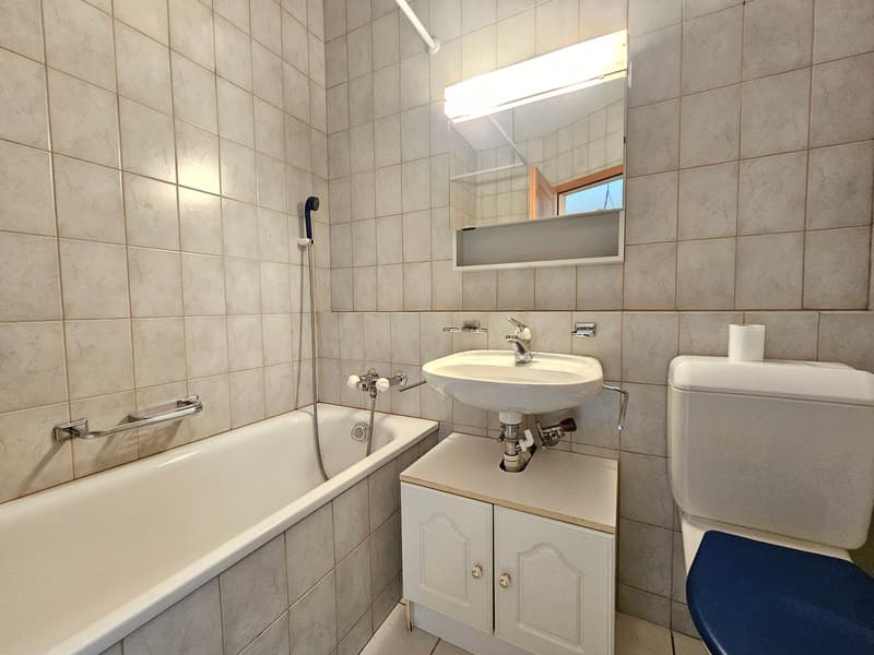 Bathroom with bathtub, sink, toilet, mirror with light