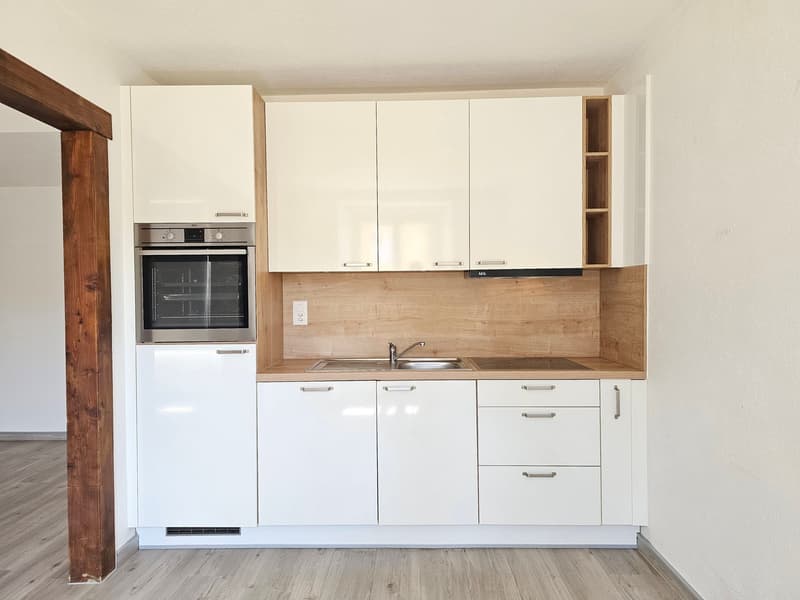 Modern kitchen with white cabinets, wooden countertop, built-in oven, and dishwasher