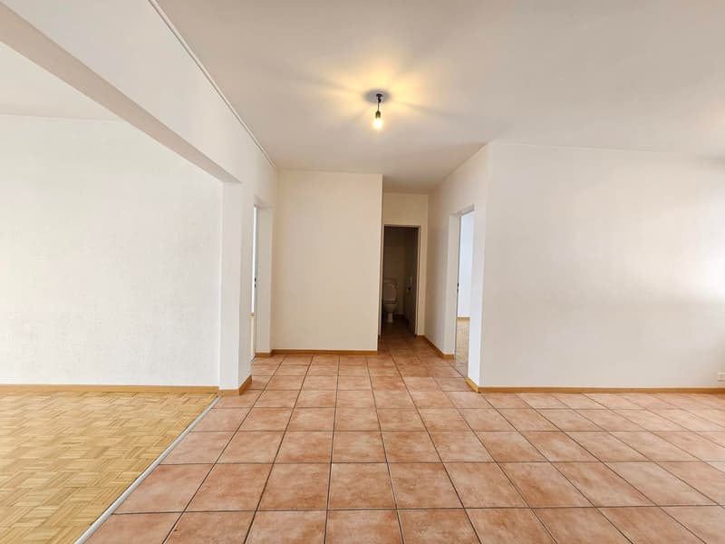 empty room, brown tile flooring, white walls, small bathroom with toilet