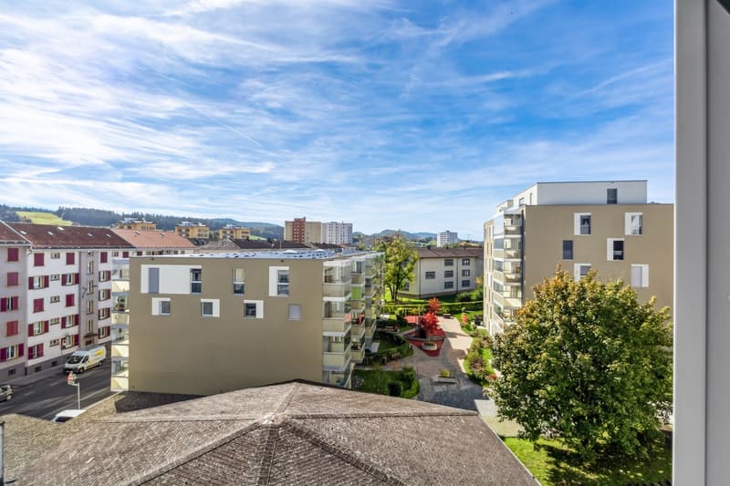 Aerial view of a residential area with multiple buildings, a garden, and a clear blue sky.