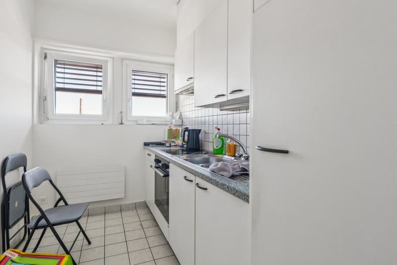 compact kitchen, white tiled flooring, windows, gas stove, sink, dishwasher, refrigerator, countertop, shelves