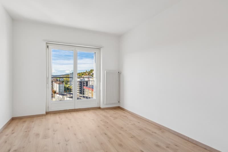 empty room, wooden floor, white walls, sliding doors to balcony, window to view