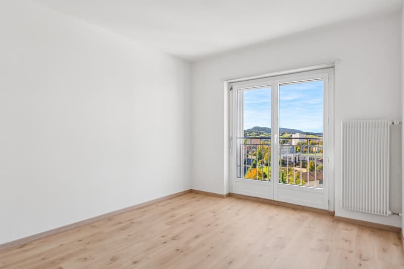 Empty room with wooden floor, sliding door, balcony, radiator, large window