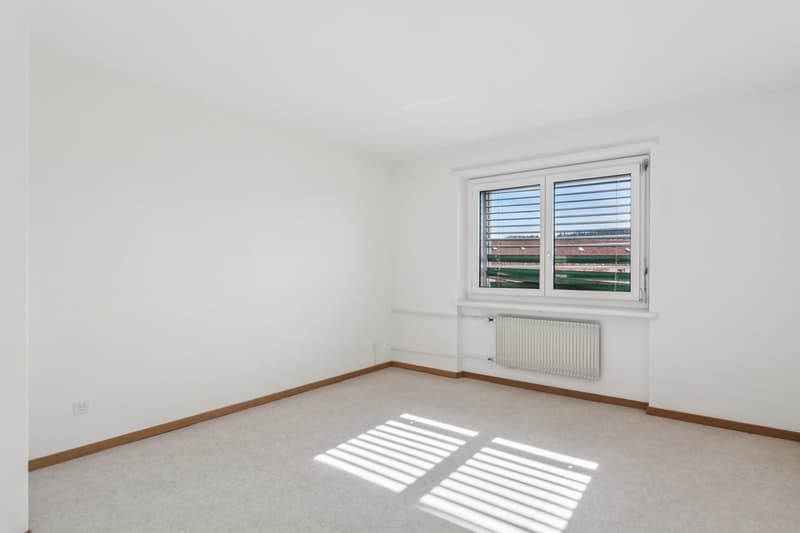 large room, white walls, white flooring, white windows with white blinds, heating unit