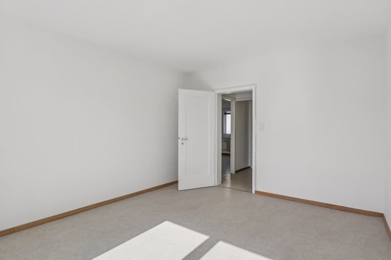 empty room, white walls, wooden floor trim, open door, small hallway, closed door