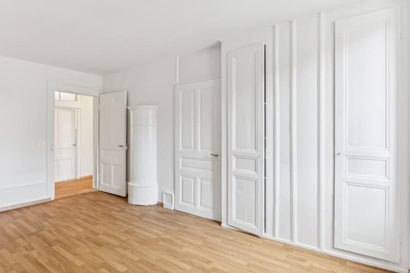 white walls, hardwood floors, white doors, large column