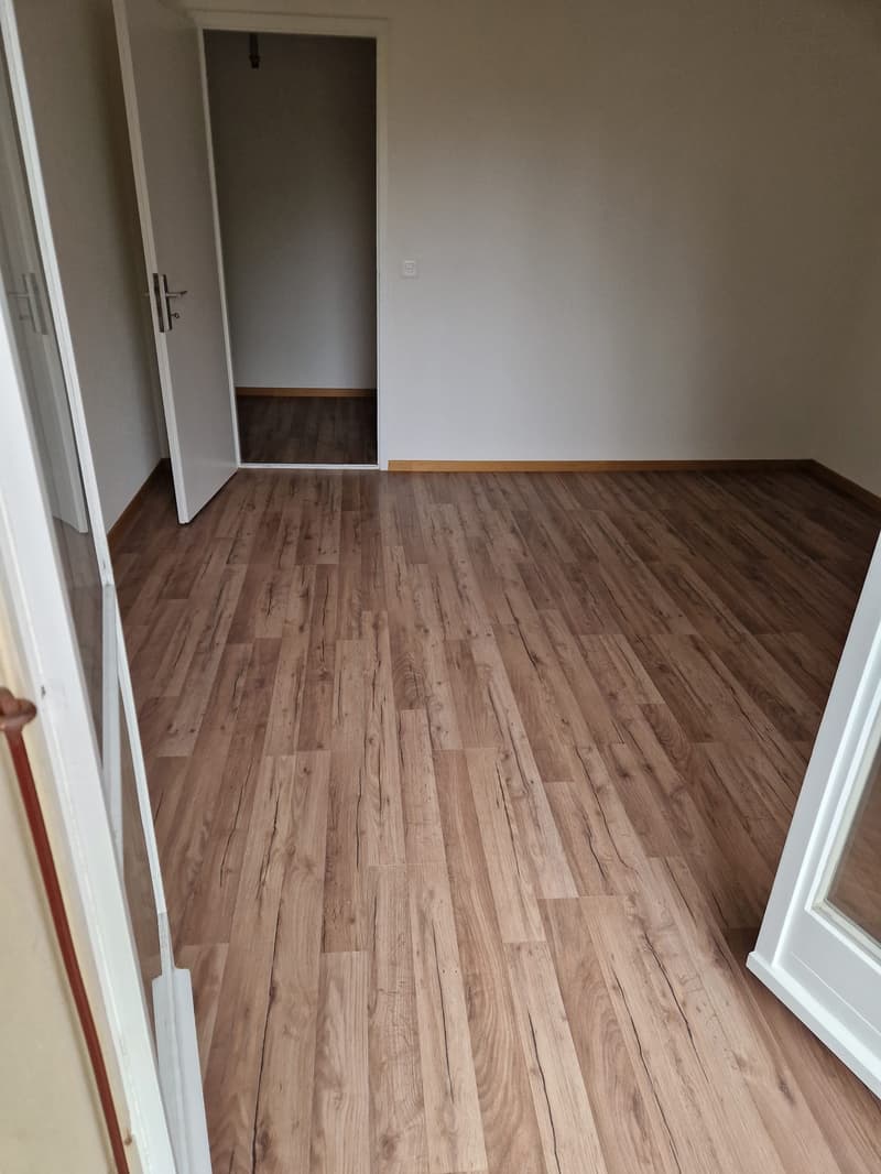 Empty room, wooden floors, white walls, open doors, power outlet on wall
