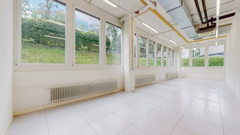 a large room with white tiles, large windows, and heaters