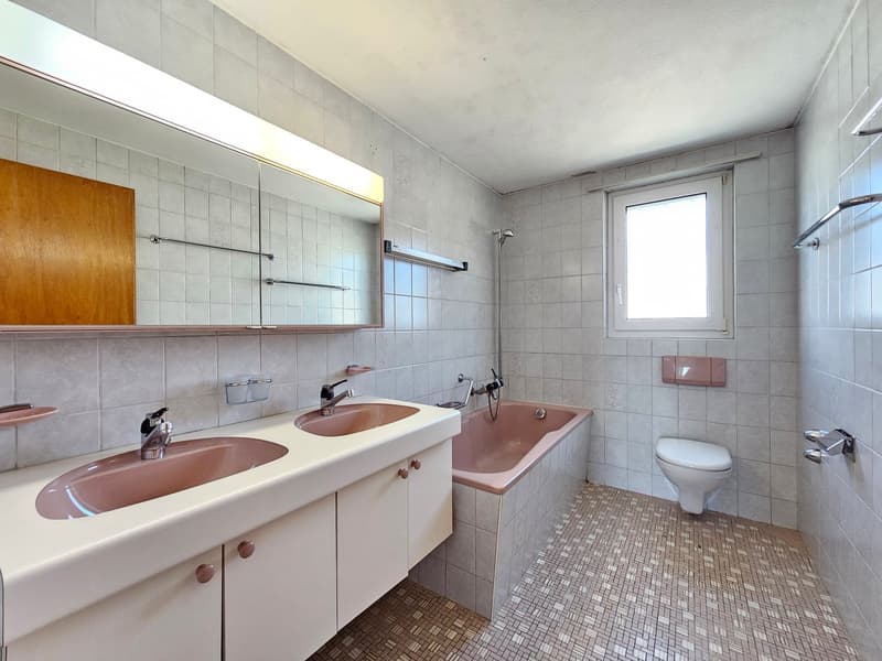 Bathroom with two sinks, bathtub, toilet, mirror, and tiled floor.