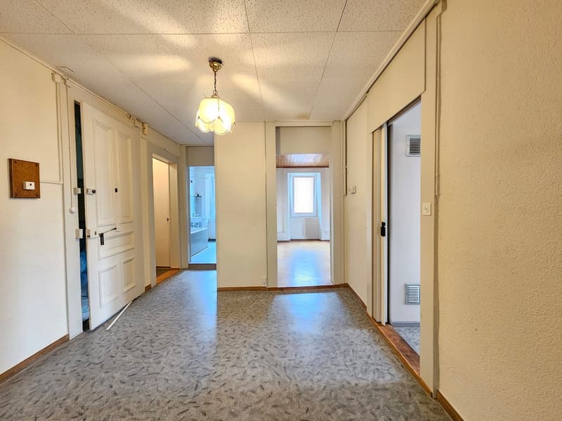 empty corridor, white walls, gray carpet, open doors, single light fixture